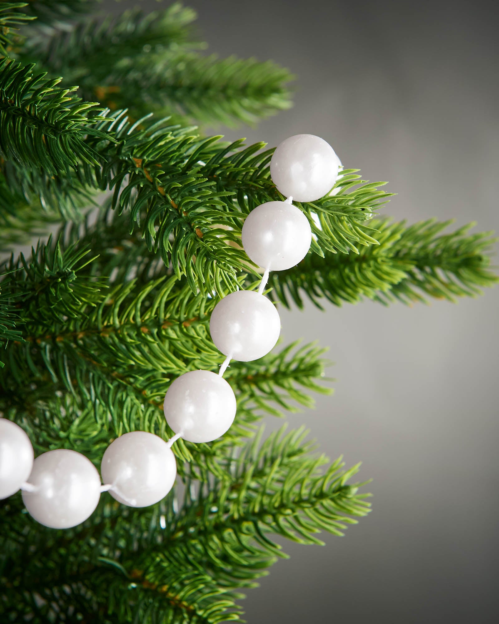 Close-up of glossy white beads on a 2.7m oversized garland displayed on a Christmas tree.