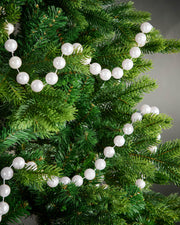 2.7m white oversized beaded garland draped through green Christmas tree branches.