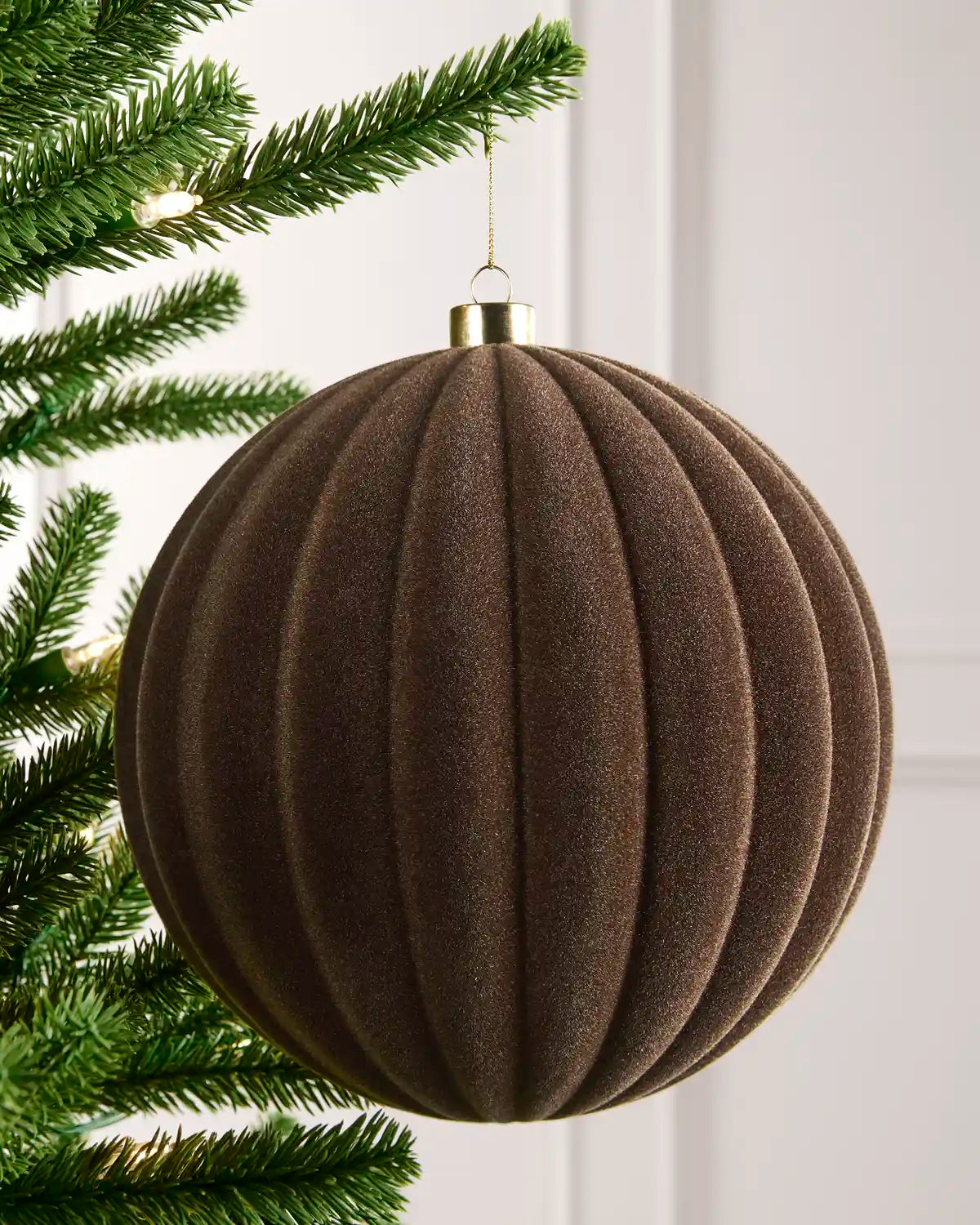 20 cm Mocha oversized velvet Ribbed bauble hanging from a Christmas tree with a gold cap.
