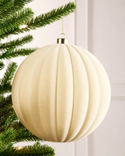 20 cm latte oversized velvet Ribbed bauble hanging from a Christmas tree with a gold cap.
