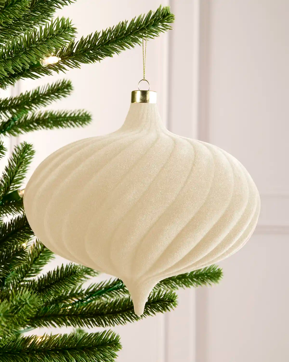 20 cm latte oversized velvet Spiral bauble hanging from a Christmas tree with a gold cap.
