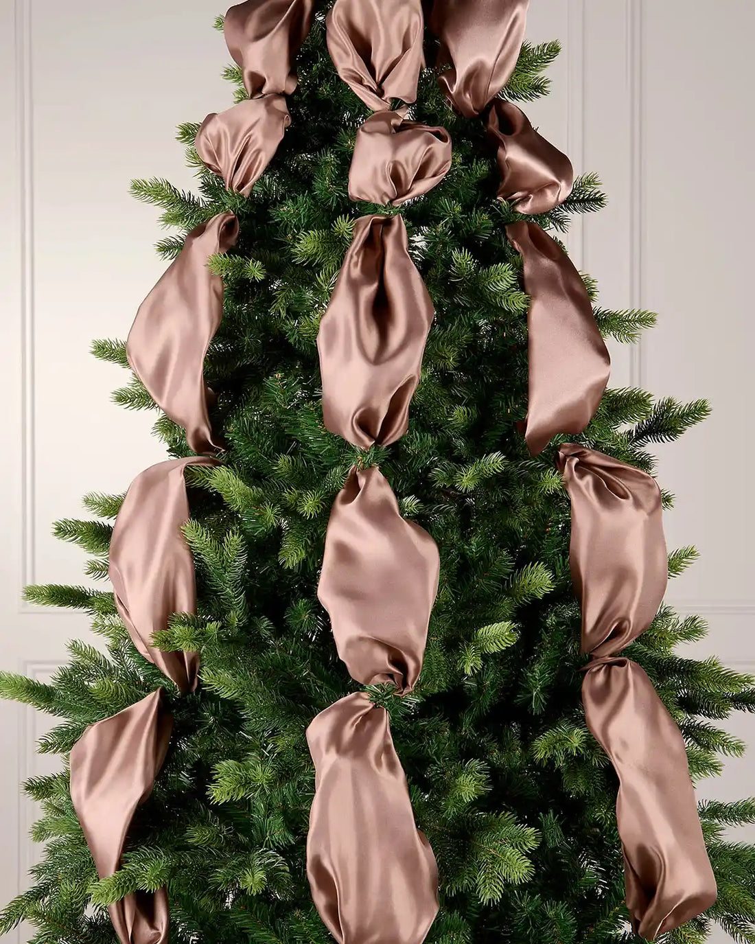 Mocha satin ribbon woven through a Christmas tree as part of a festive indoor display.