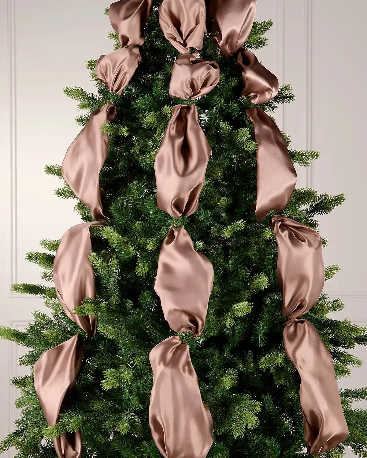 Mocha satin ribbon woven through a Christmas tree as part of a festive indoor display.