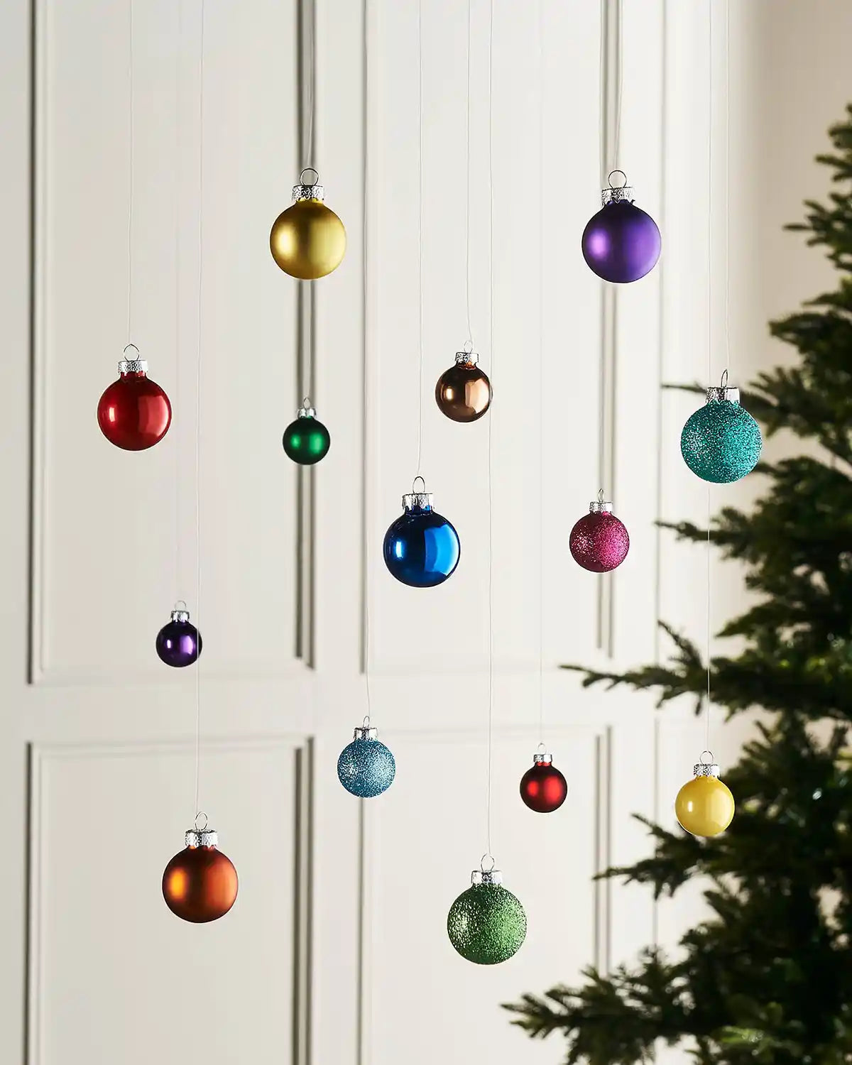 Multi-coloured mini glass baubles hanging in a festive indoor display