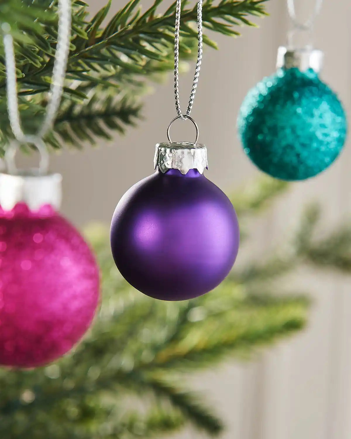 Close-up of a purple mini glass bauble hanging on a Christmas tree