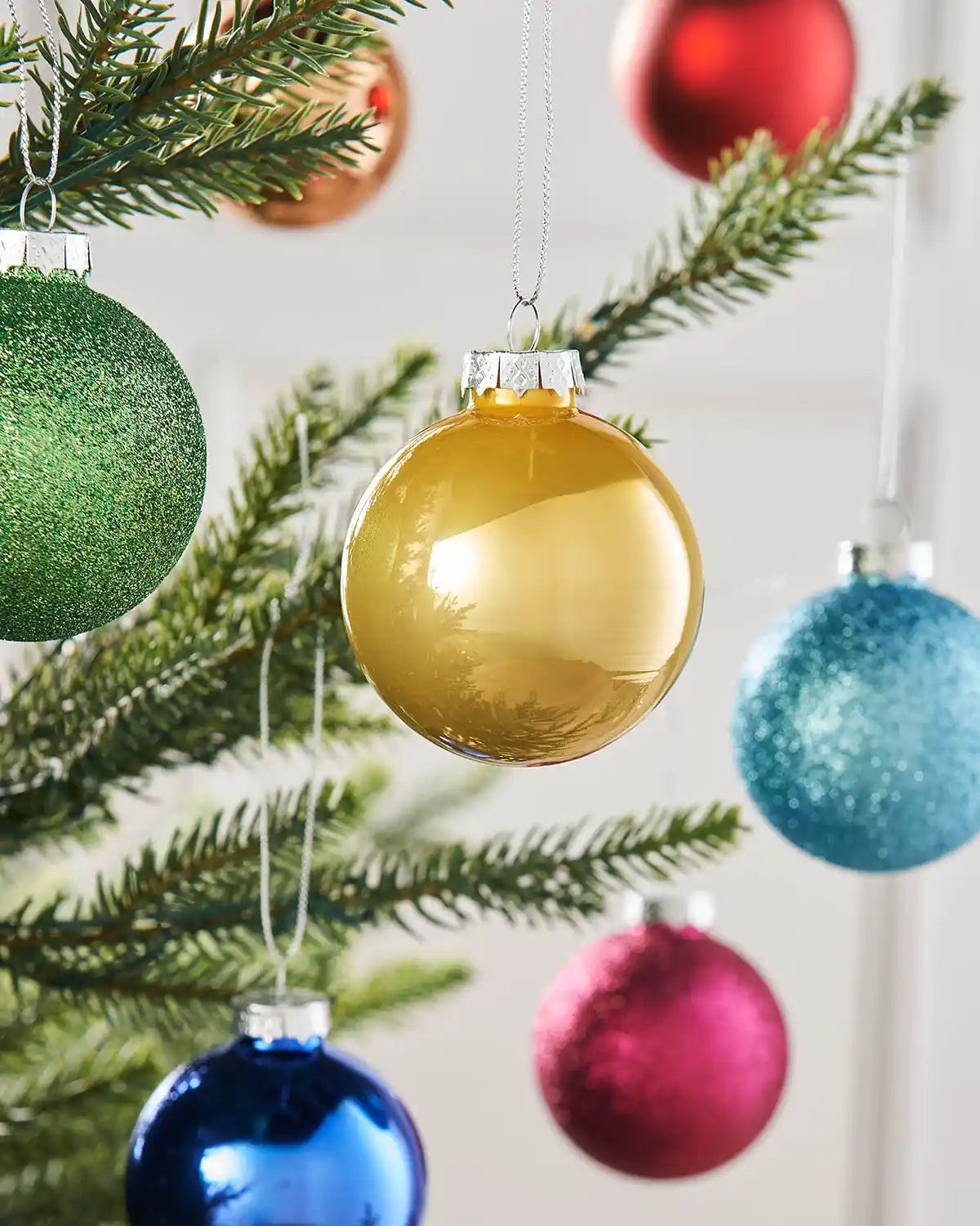 Gold and multi-coloured glass baubles styled on a Christmas tree