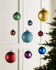 Multi-coloured 6 cm glass baubles hanging in a festive indoor display