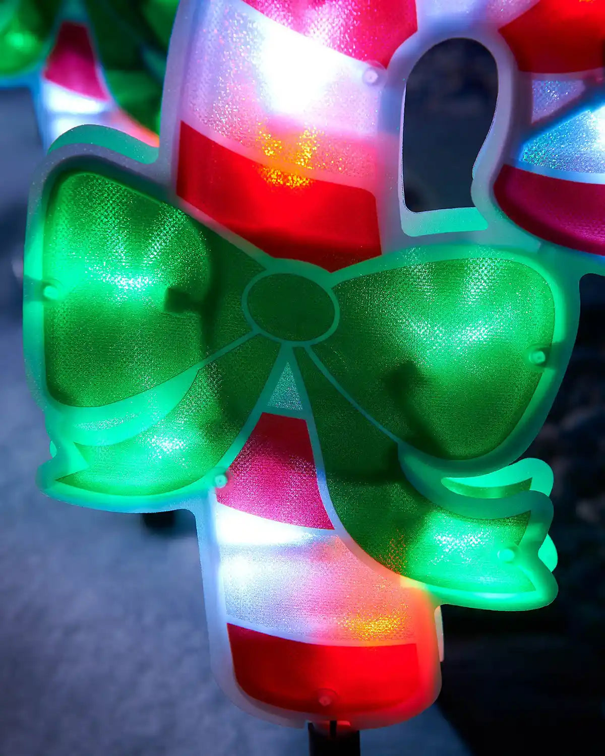 Close-up of the green bow and striped candy cane design on a pathway light