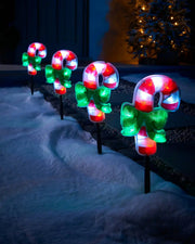 Set of four 24 cm pre-lit candy cane pathway lights displayed outdoors in snow