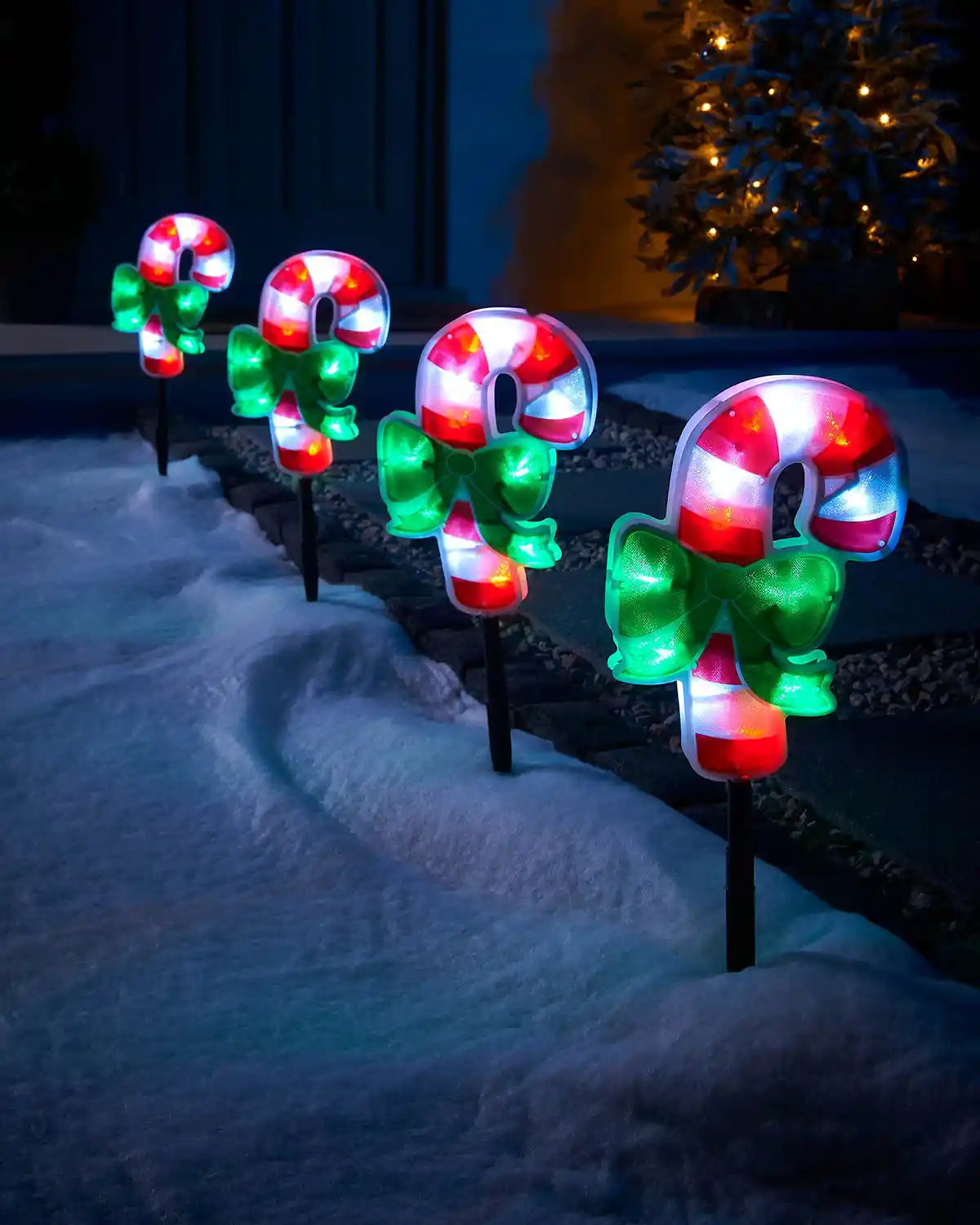 Set of four 24 cm pre-lit candy cane pathway lights displayed outdoors in snow