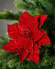 24cm red glitter-edge artificial poinsettia flower attached to Christmas tree in front of grey wall background