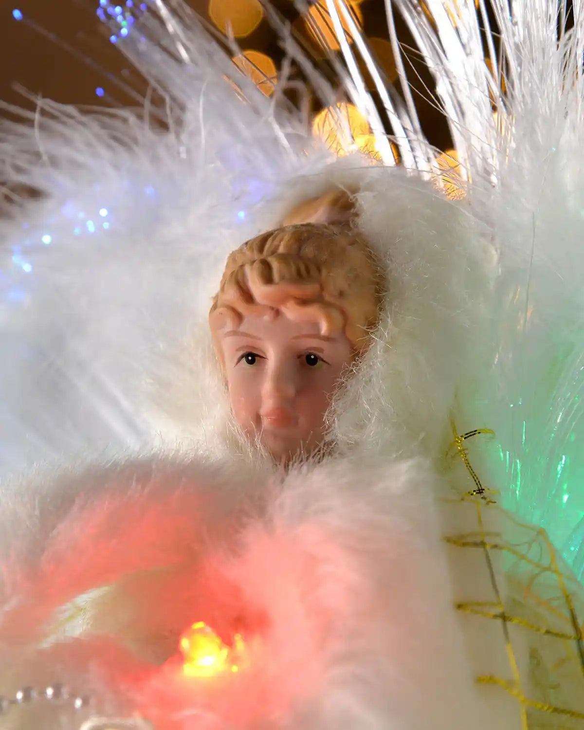 Close-up of the fibre optic angel tree topper with feathered wings, blonde hair and coloured lights
