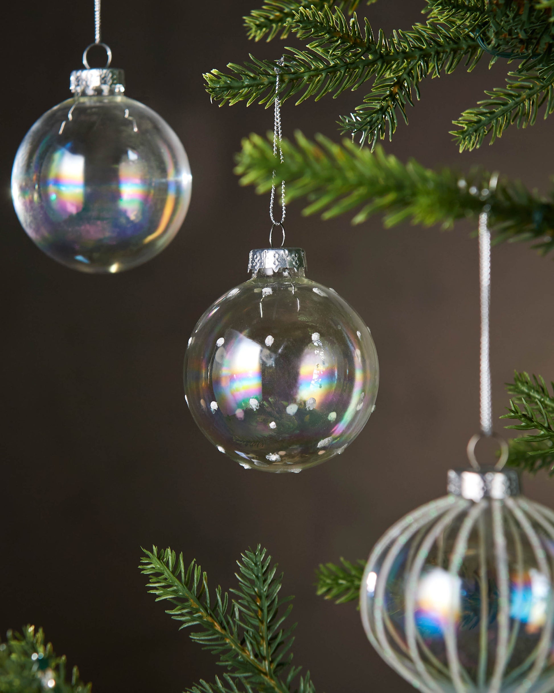 Decorative glass ornaments hanging on a Christmas tree with a dark 