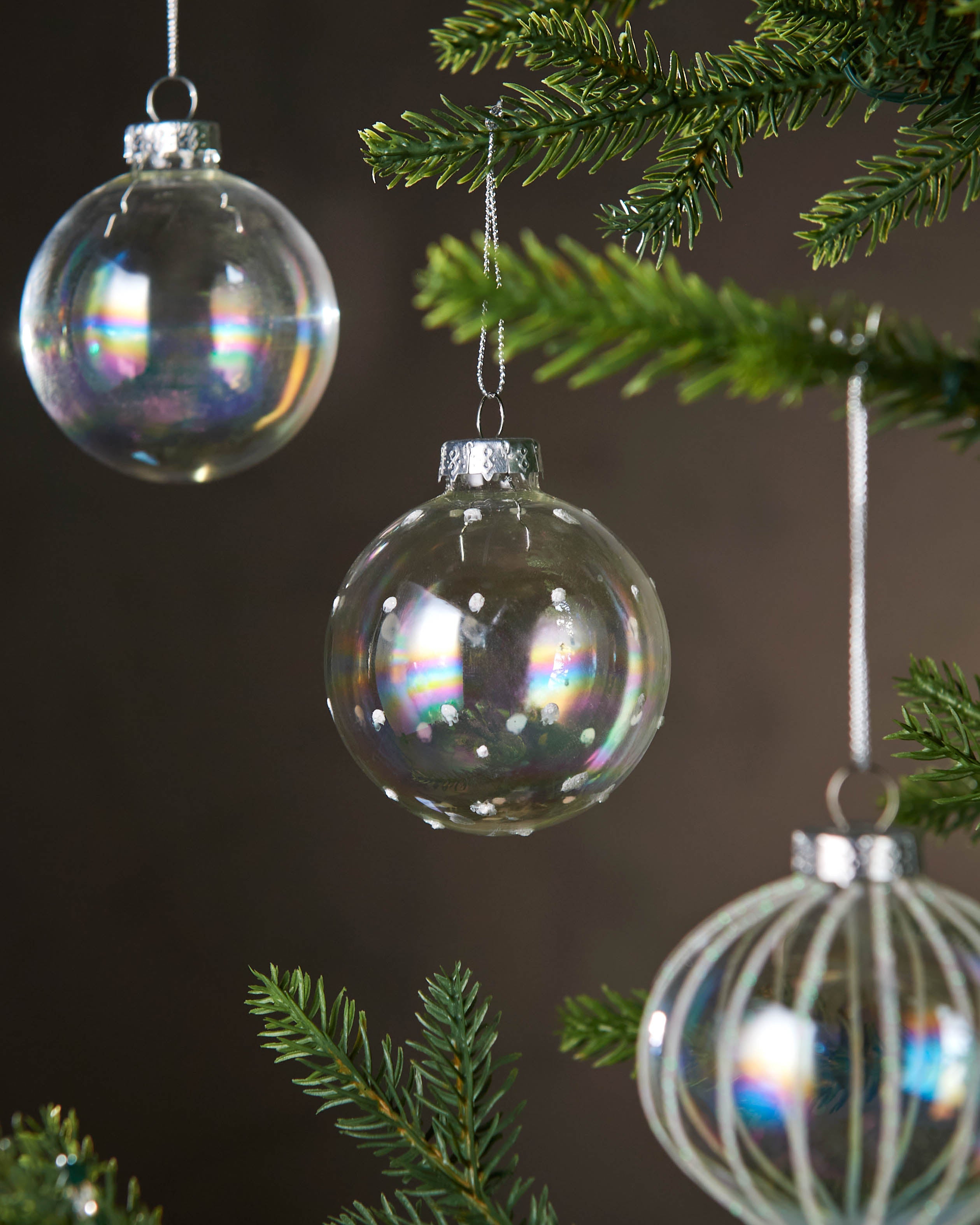 Decorative glass ornaments hanging on a Christmas tree with a dark 