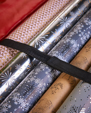 A red storage bag with white and green striped patterns, opened on the floor to display its contents of wrapped gifts.