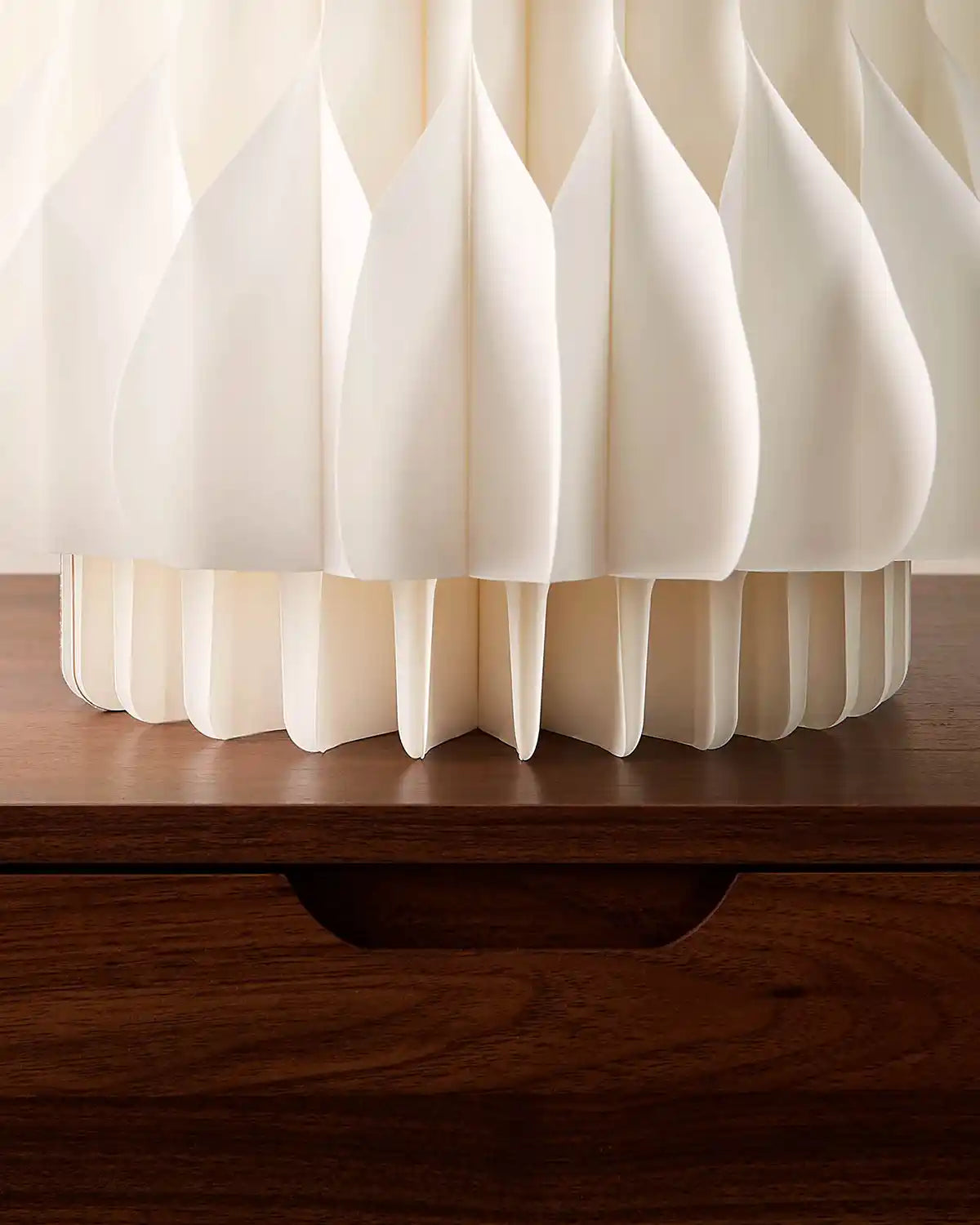 Base detail of a 2ft off-white paper honeycomb Christmas tree standing on a wooden surface.