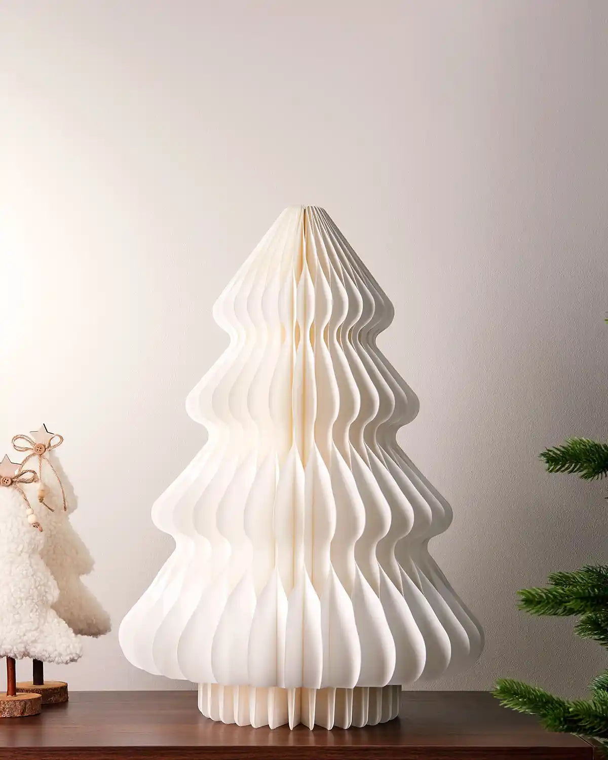 2ft off-white paper honeycomb Christmas tree on a tabletop with festive décor nearby.
