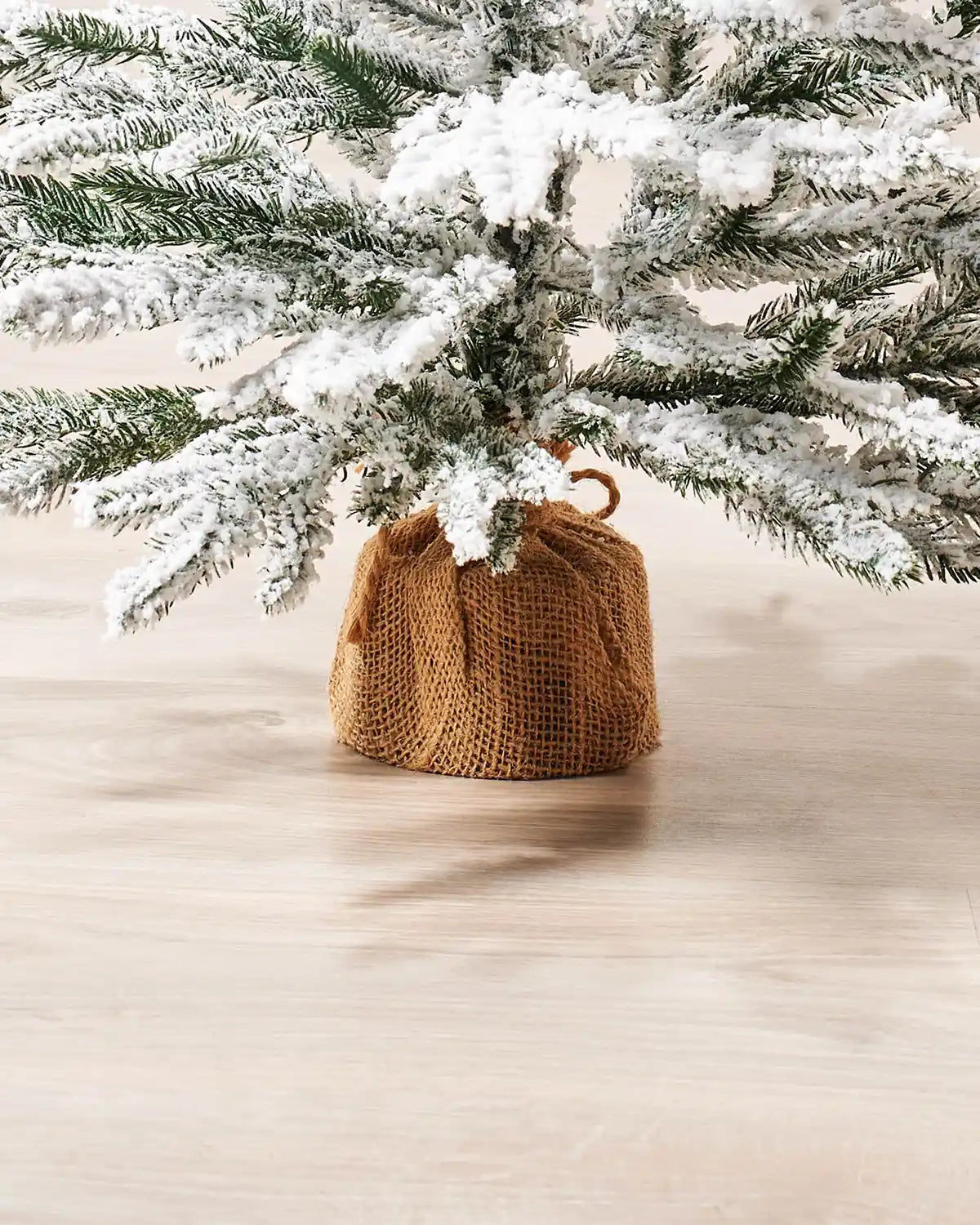 Close up of the brown hessian-wrapped base on 2ft Snow flocked artificial Christmas tree.
