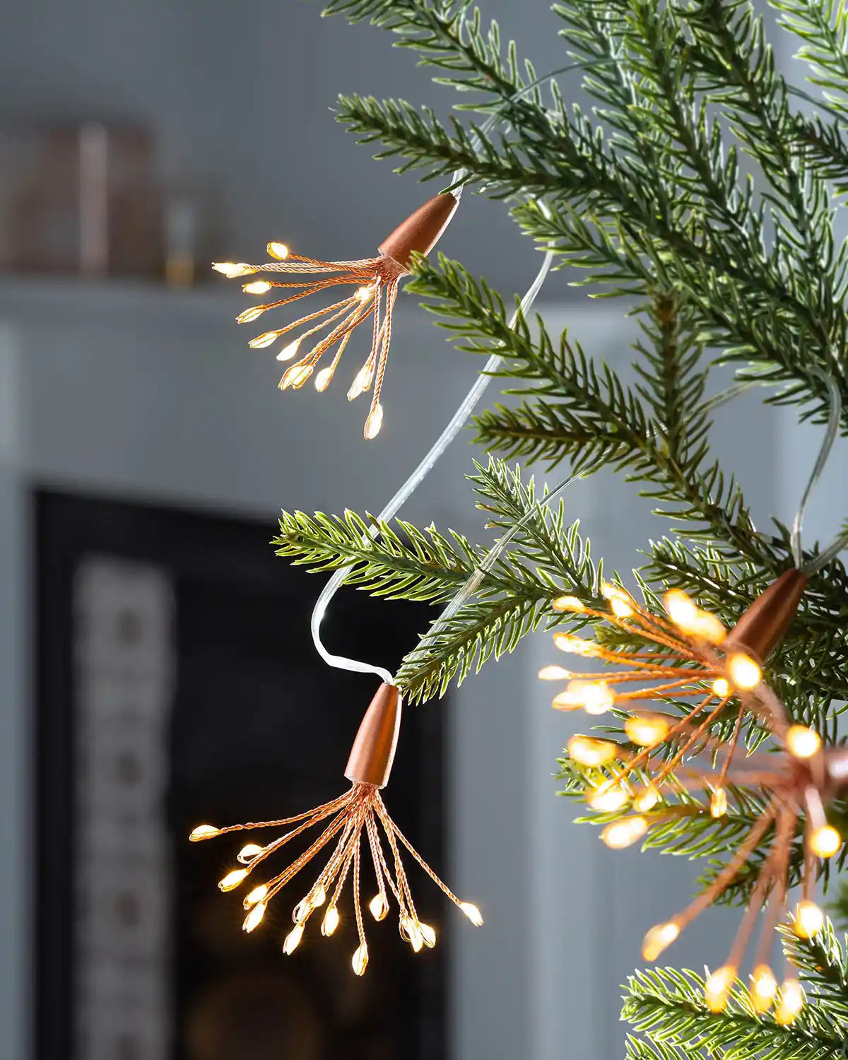 Close-up of copper wire firework lights glowing warm white on a Christmas tree