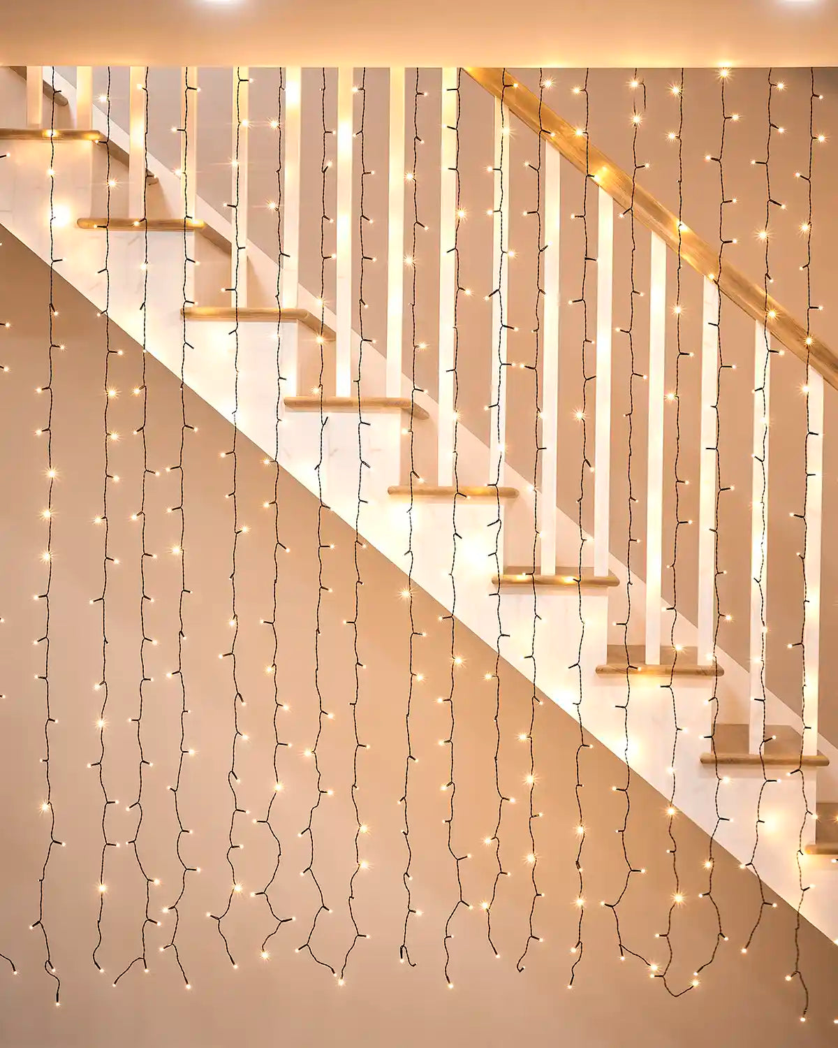 Warm white curtain lights on black cable displayed across a staircase wall.