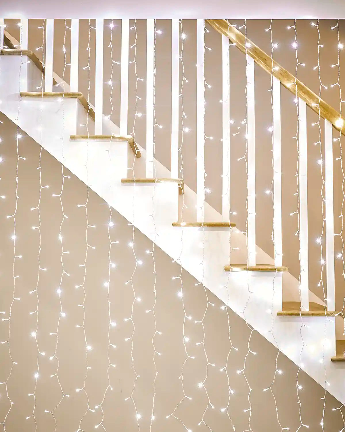 White curtain lights on white cable displayed along a staircase bannister.