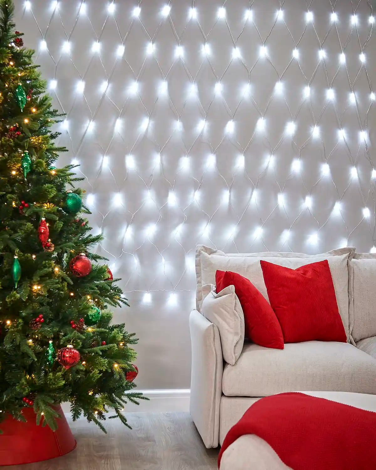 White net lights displayed on a living room wall beside a Christmas tree and sofa.