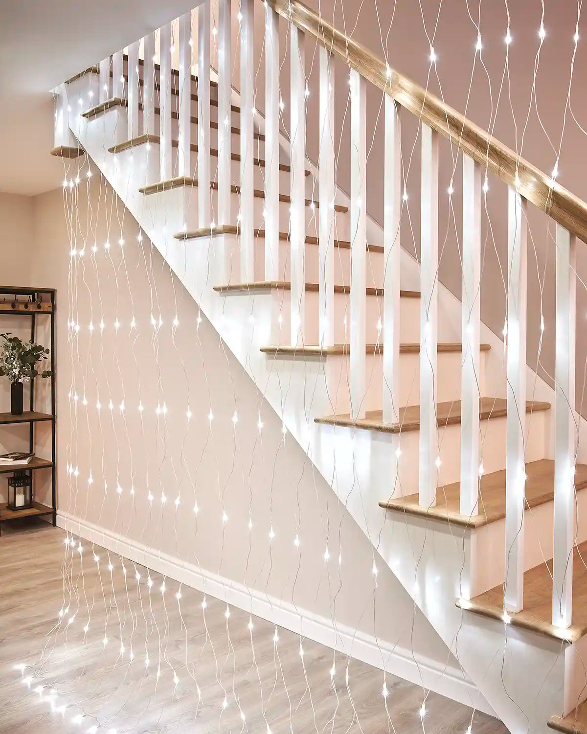 White net lights hanging beside an indoor staircase with iridescent cable.