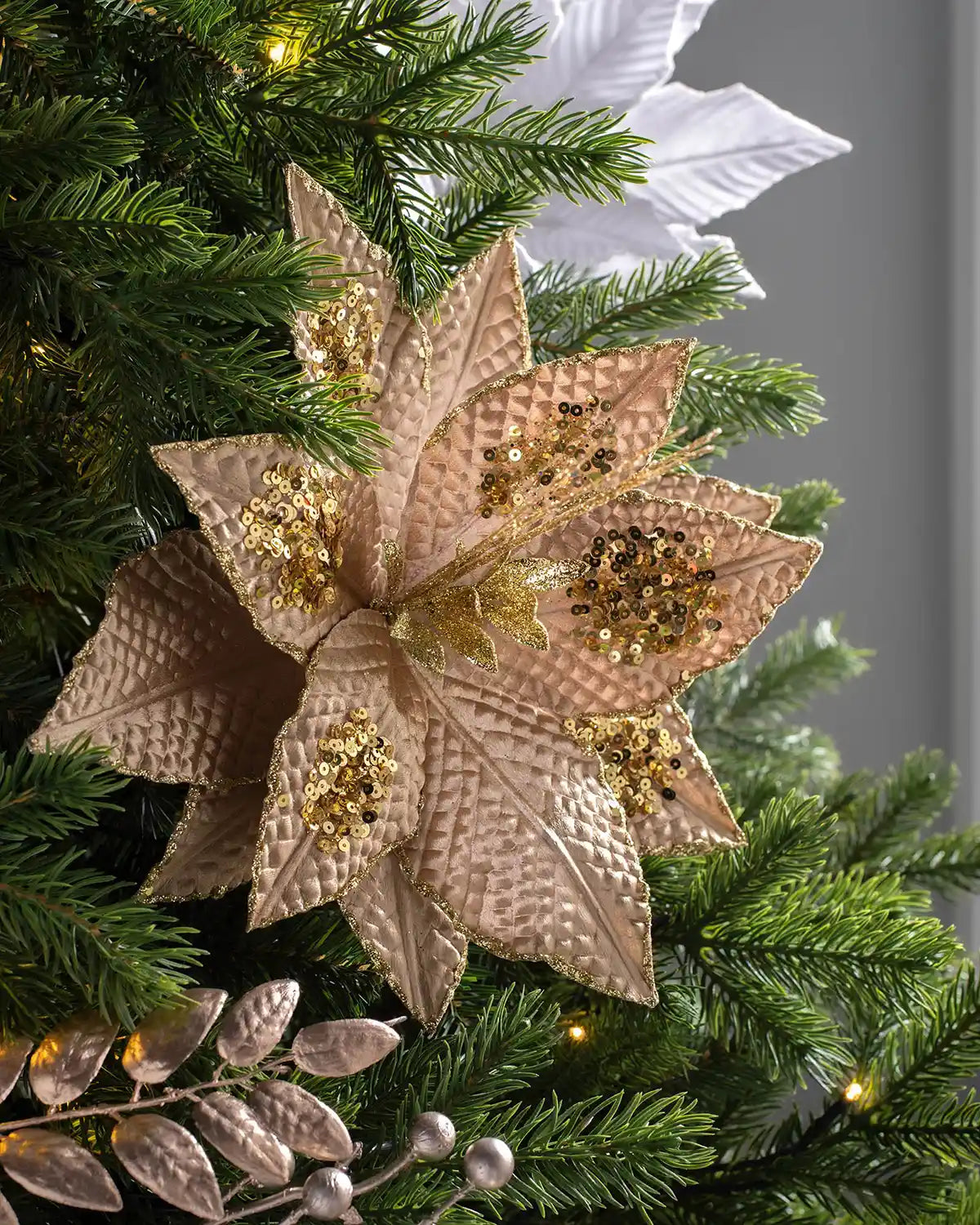 30 cm gold artificial poinsettia flower displayed in a decorated tree