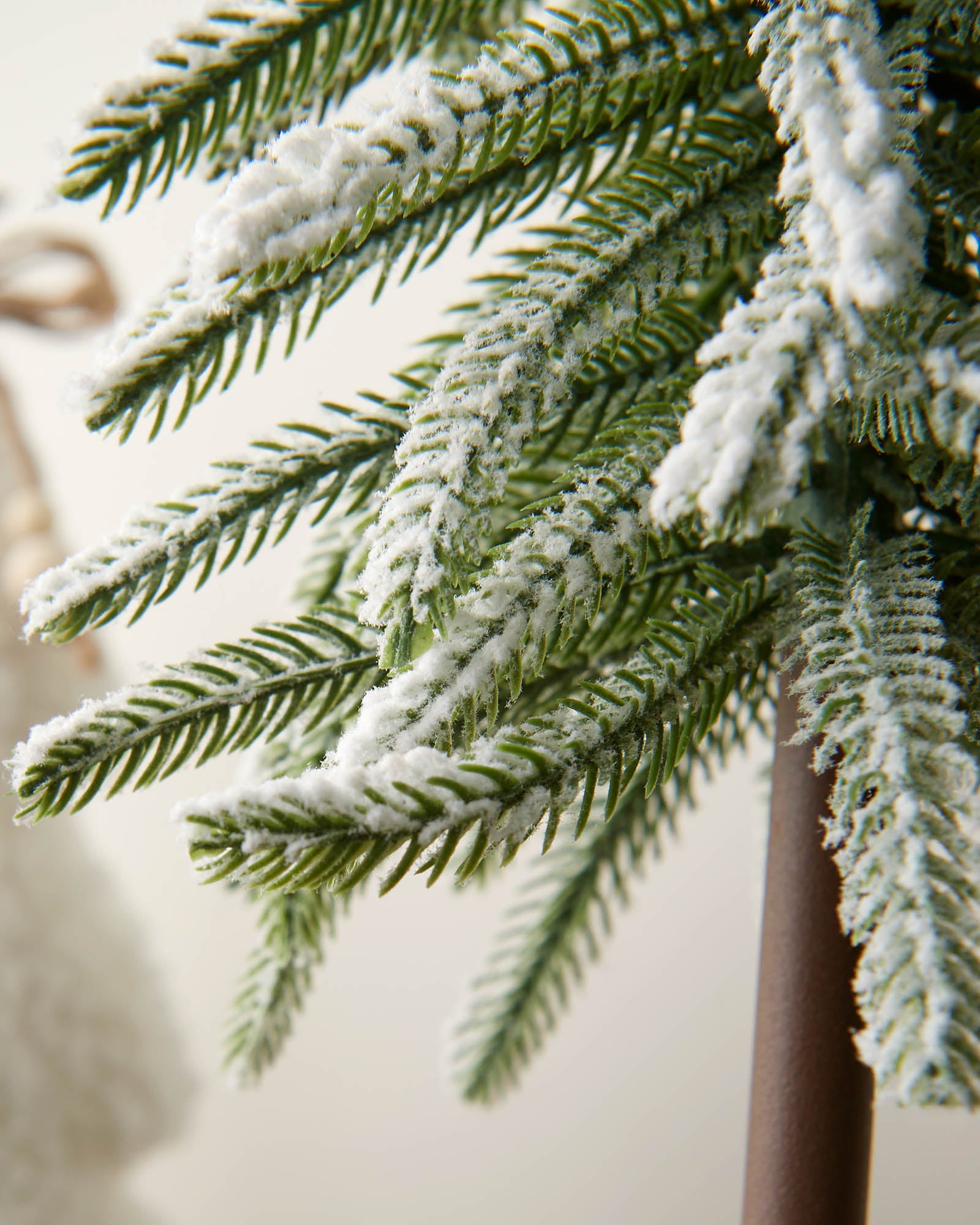 Decorative Christmas trees with snow on a wooden stand against a neutral background