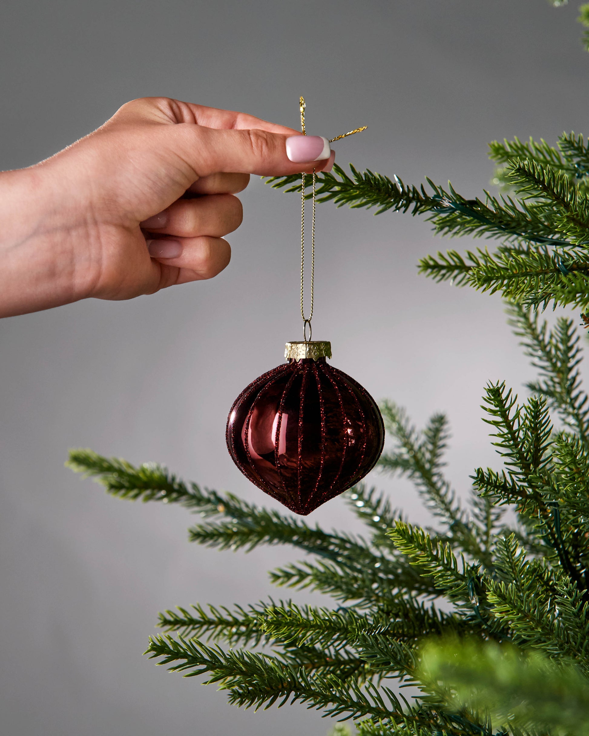 Red glass ornaments on a Christmas tree with a dark background