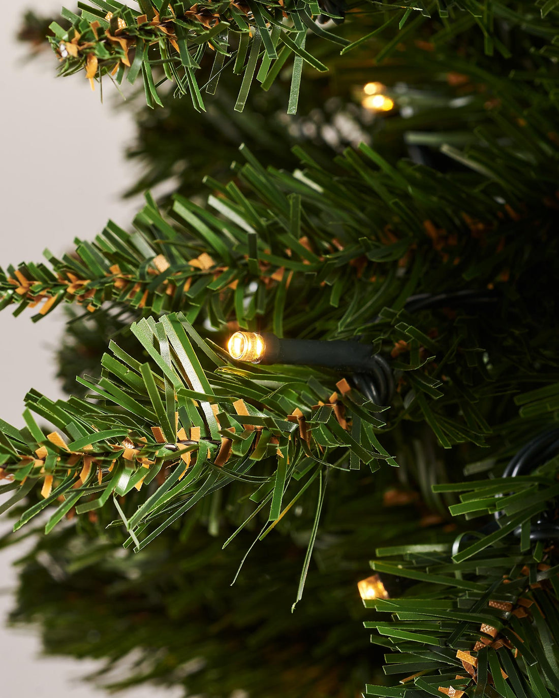 A pre-lit green wall-mounted Christmas tree with 400 bullet tips and 100 warm white LED lights, featuring a compact 3 ft height and 55 cm diameter. The tree is illuminated with multi-functional lighting settings and designed to save space while adding festive warmth.