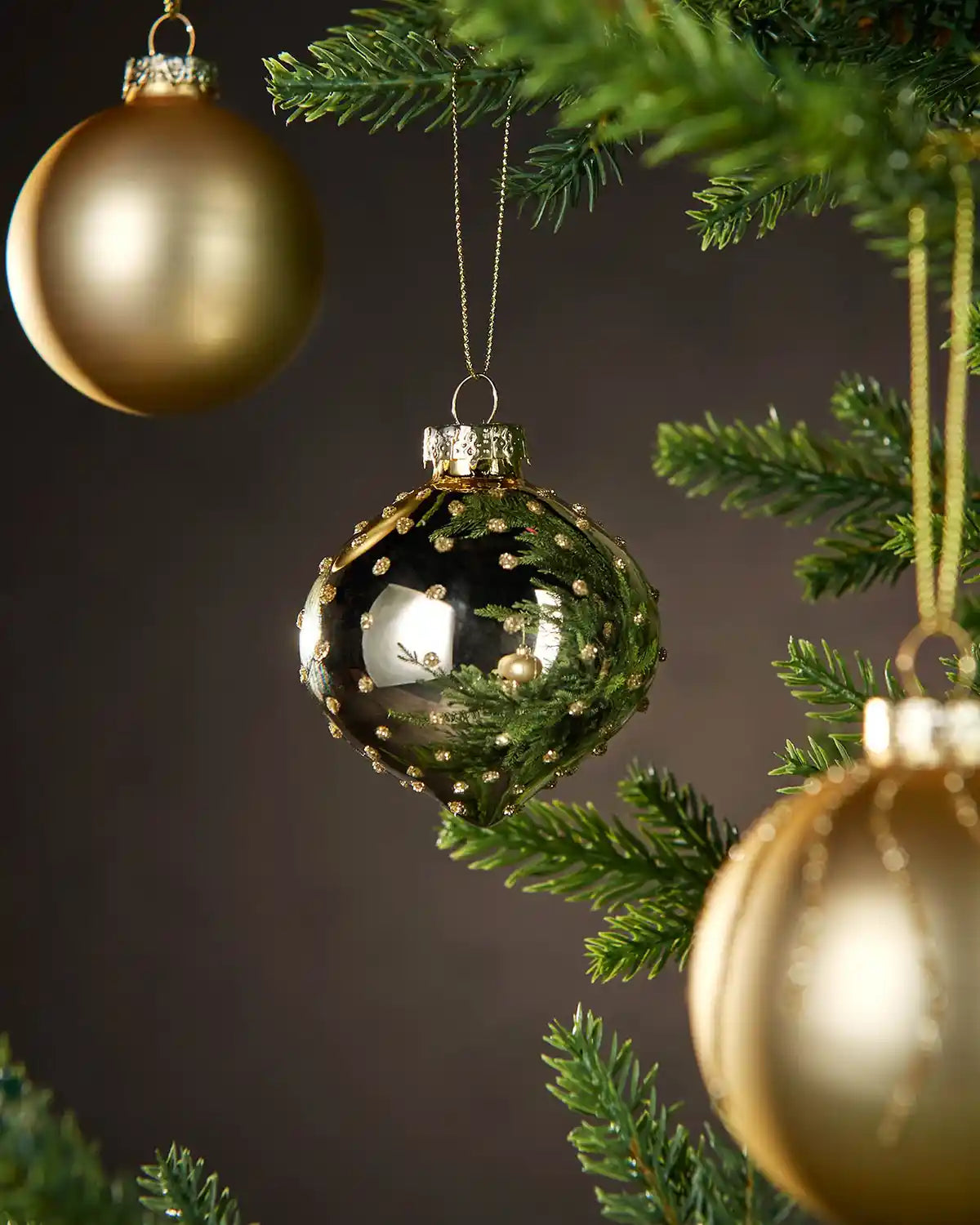 3 Gold Christmas baubles on a tree branch with a dark background