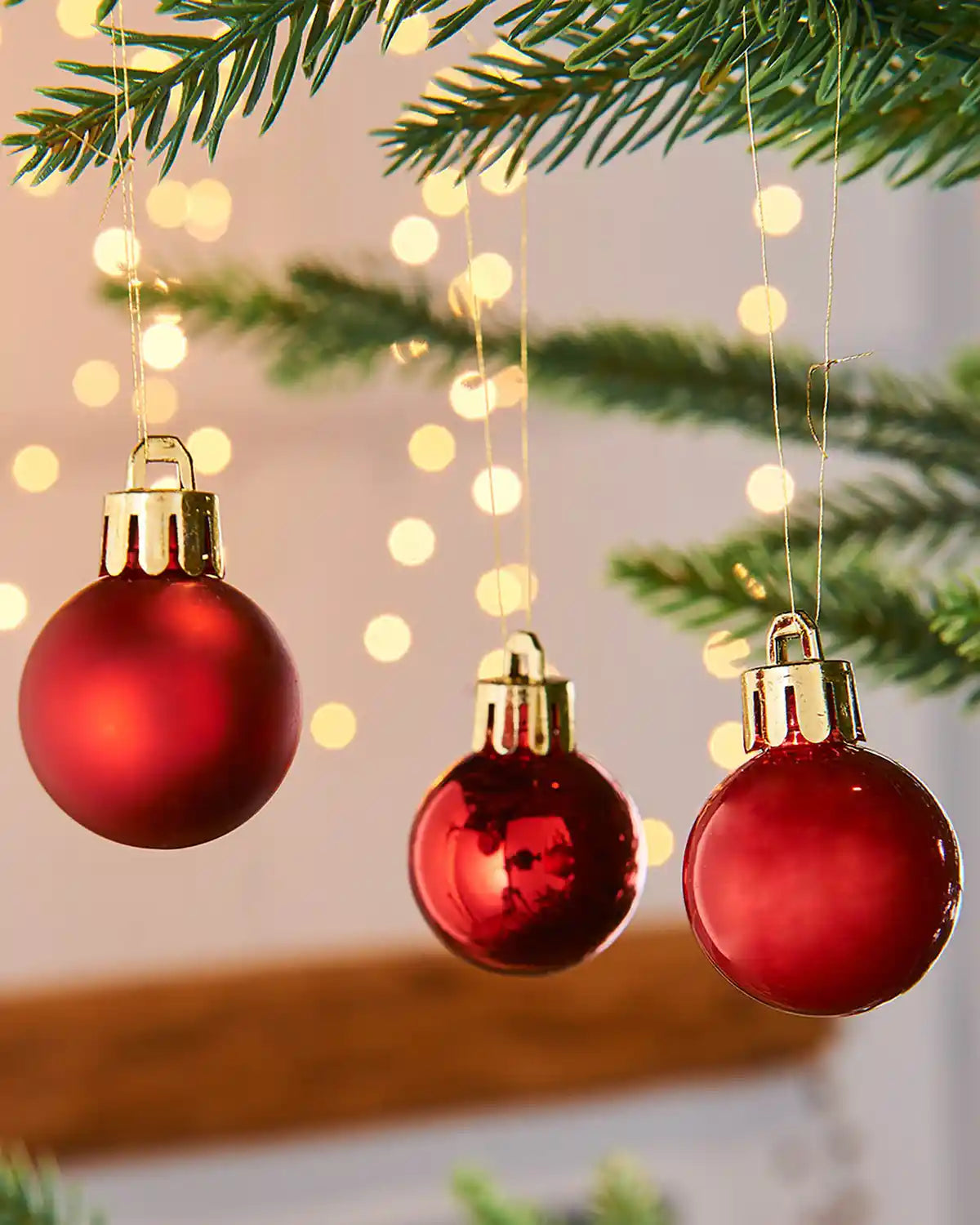 3 Red Christmas baubles on a tree with blurred lights in the background