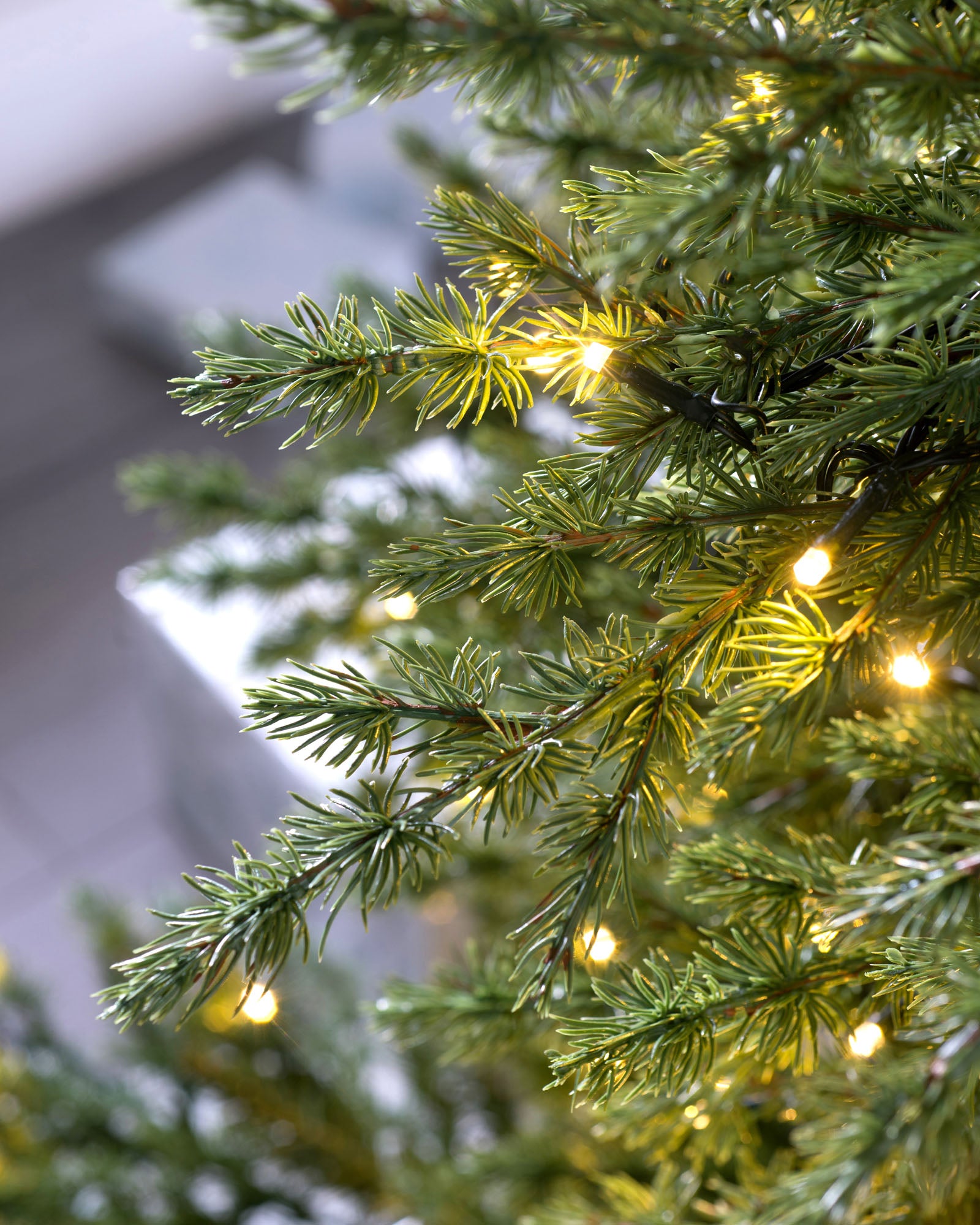 Pre-lit Traditional Fir Christmas tree with dense, mixed PE and PVC foliage, illuminated by warm white LED lights. Featuring multi-functional lighting settings and a low voltage transformer for safe indoor and outdoor use. Displayed with a lush, lifelike appearance and a classic silhouette.