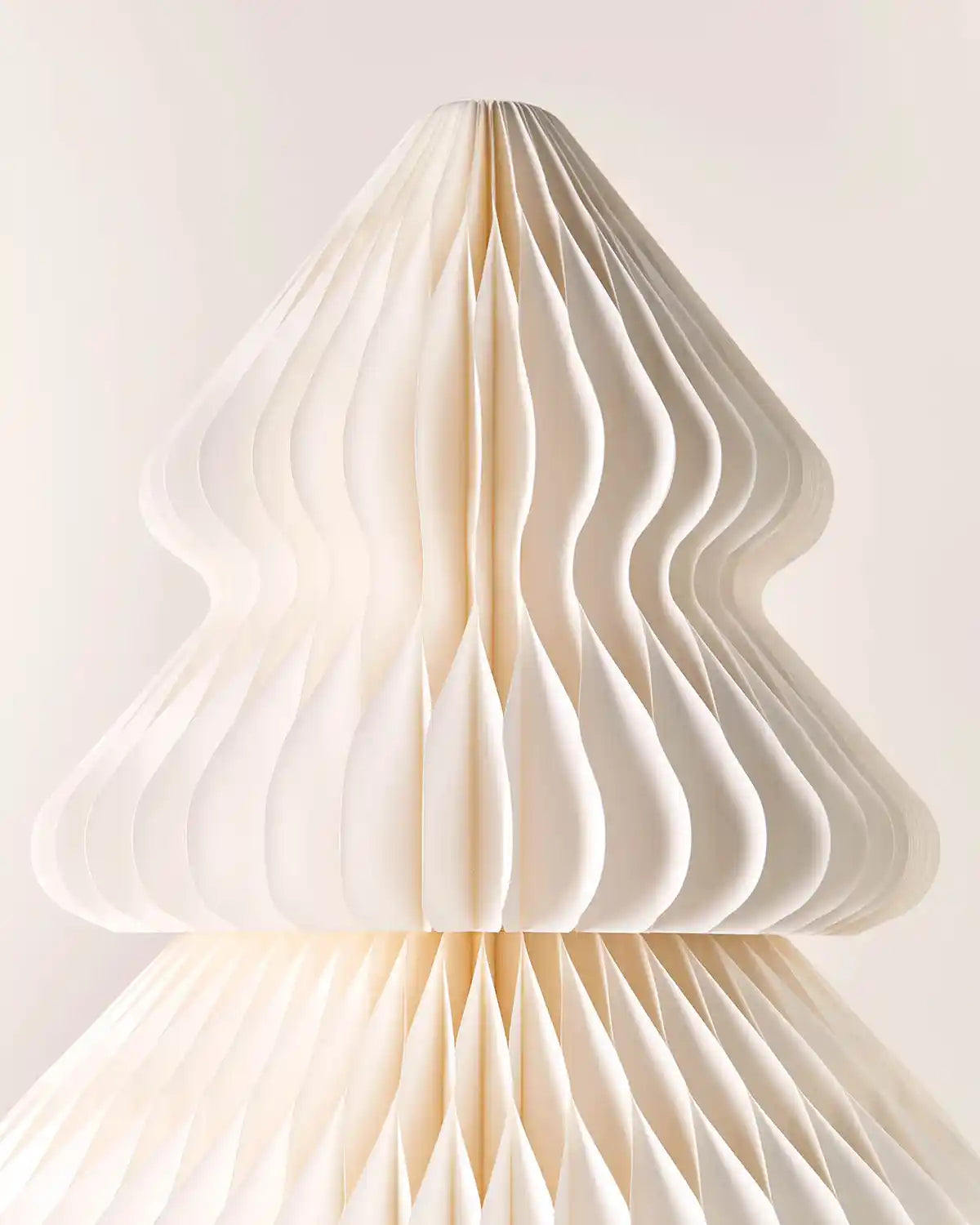 Close-up of the layered off-white paper honeycomb design on a Christmas tree decoration.