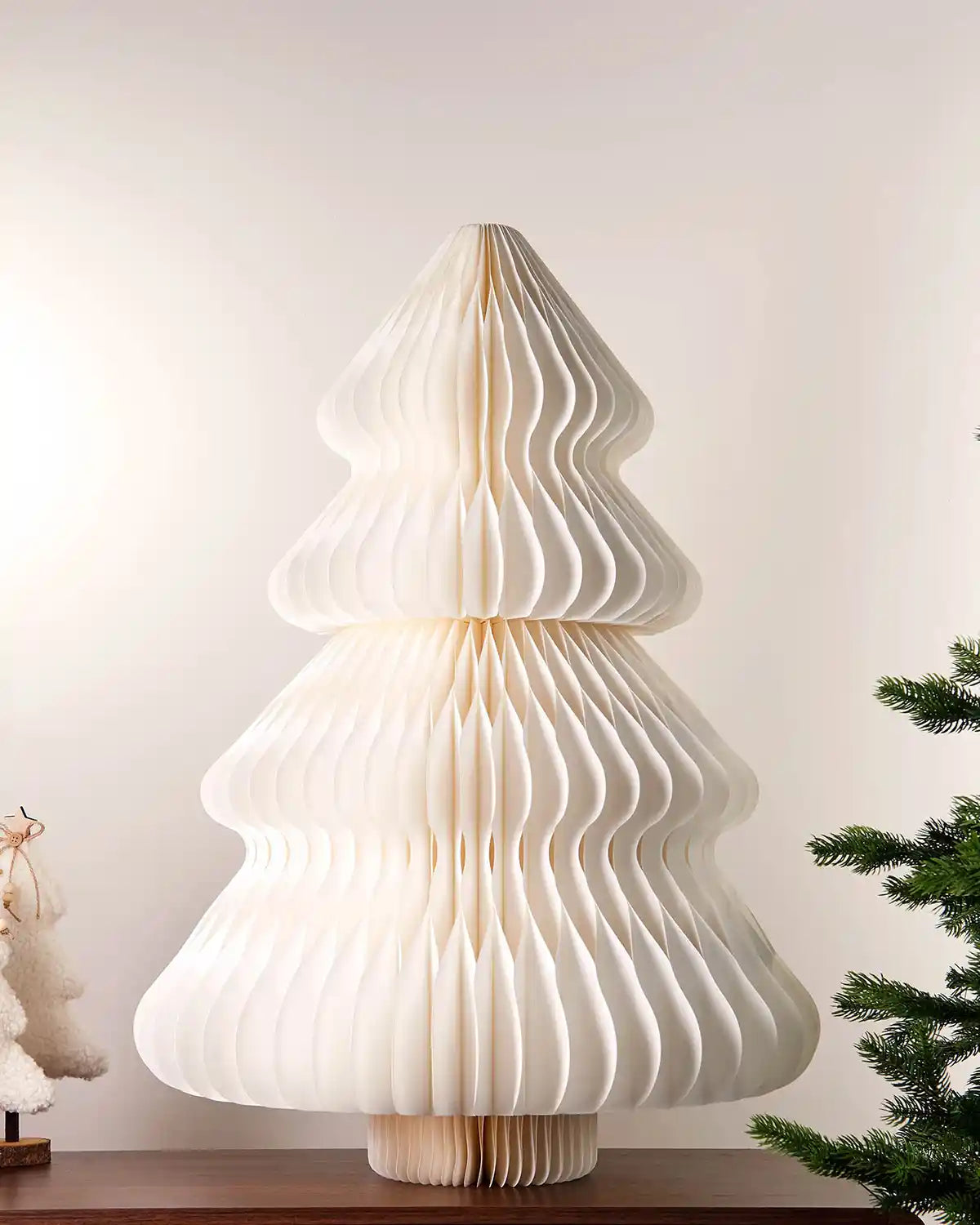 3ft off-white paper honeycomb Christmas tree on a tabletop with festive décor nearby.