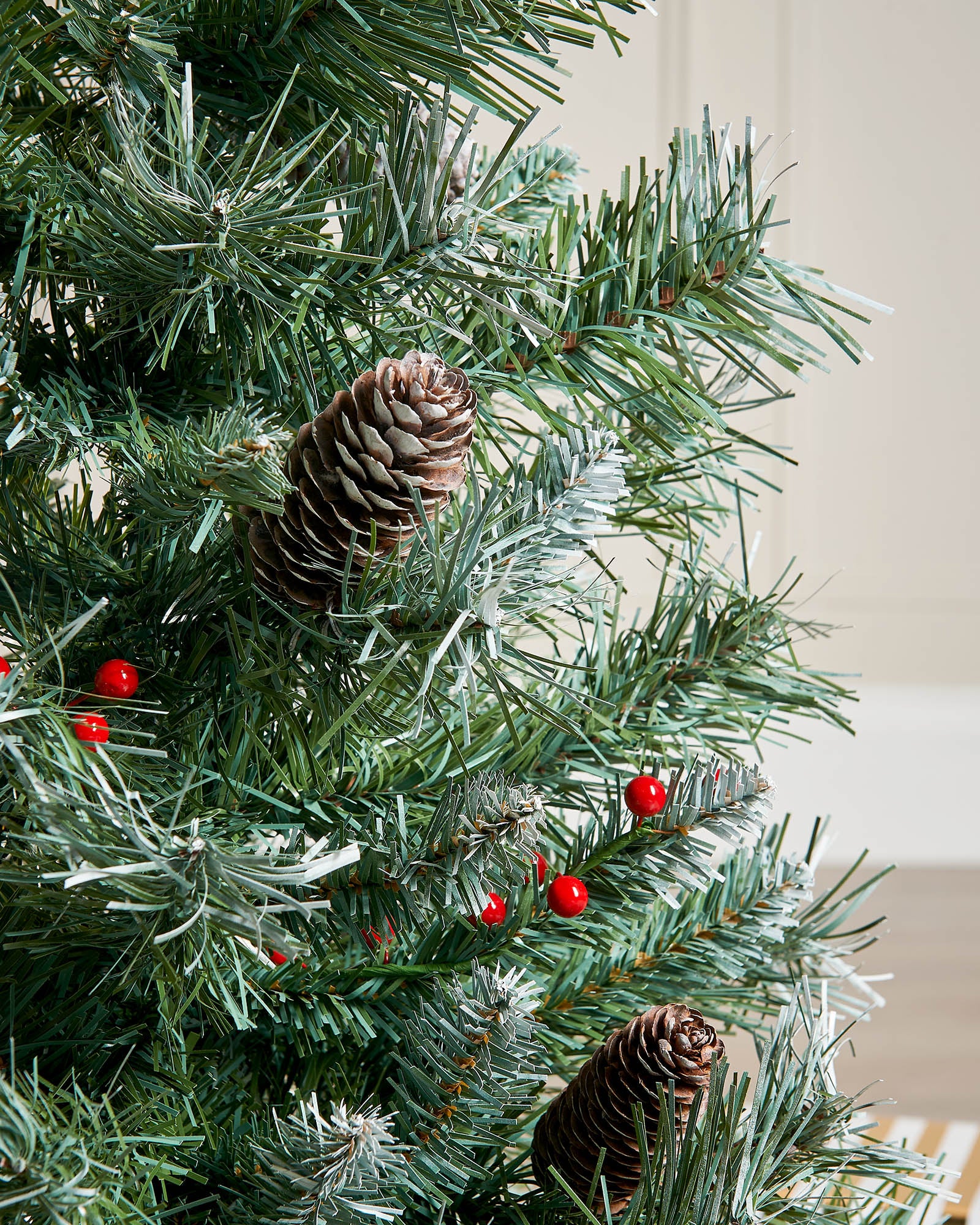 Close-up of frosted branches, pinecones and red berries on a 3 ft potted Scandinavian blue spruce Christmas tree