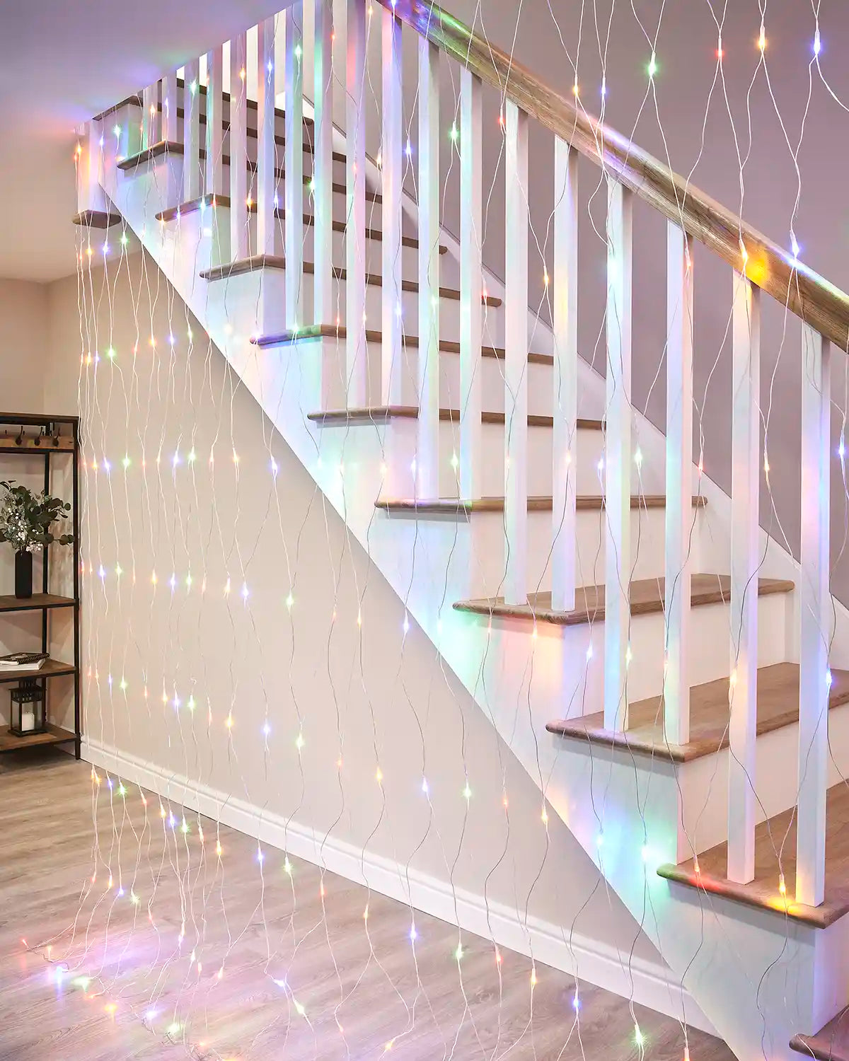 Multi-colour net lights hanging beside an indoor staircase with a transparent cable.