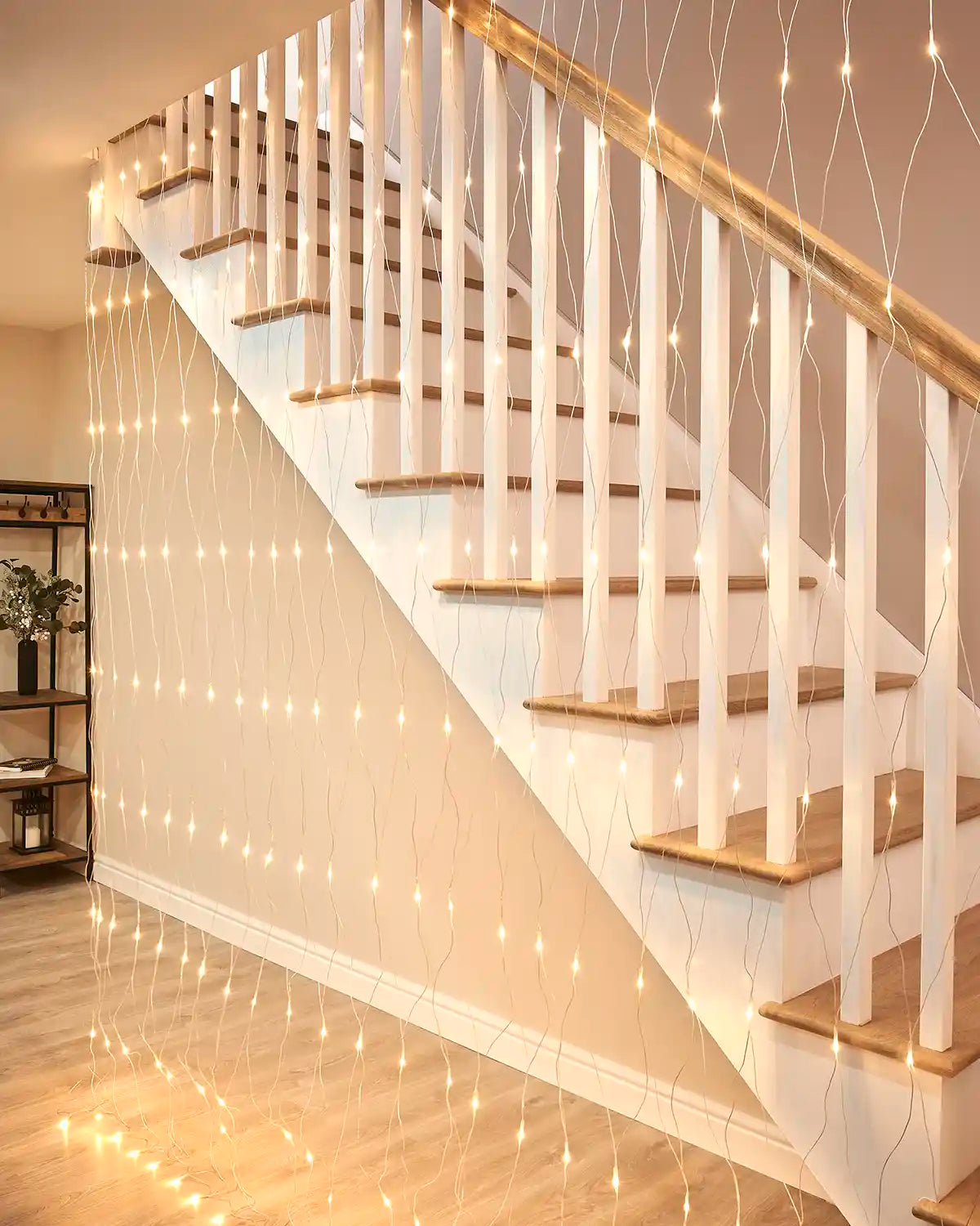 Warm white net lights hanging beside an indoor staircase with a transparent cable.