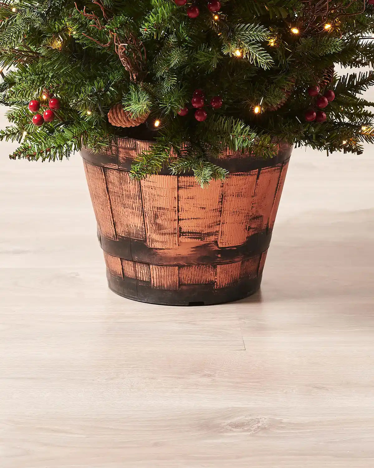 Close-up of the wooden barrel-style pot on a 4.5 ft pre-lit pines and berries Christmas tree