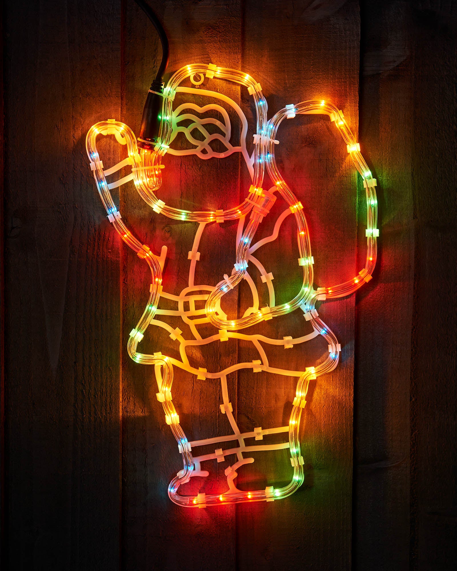 Multi-coloured Santa with gift sack rope light silhouette mounted on a wooden wall