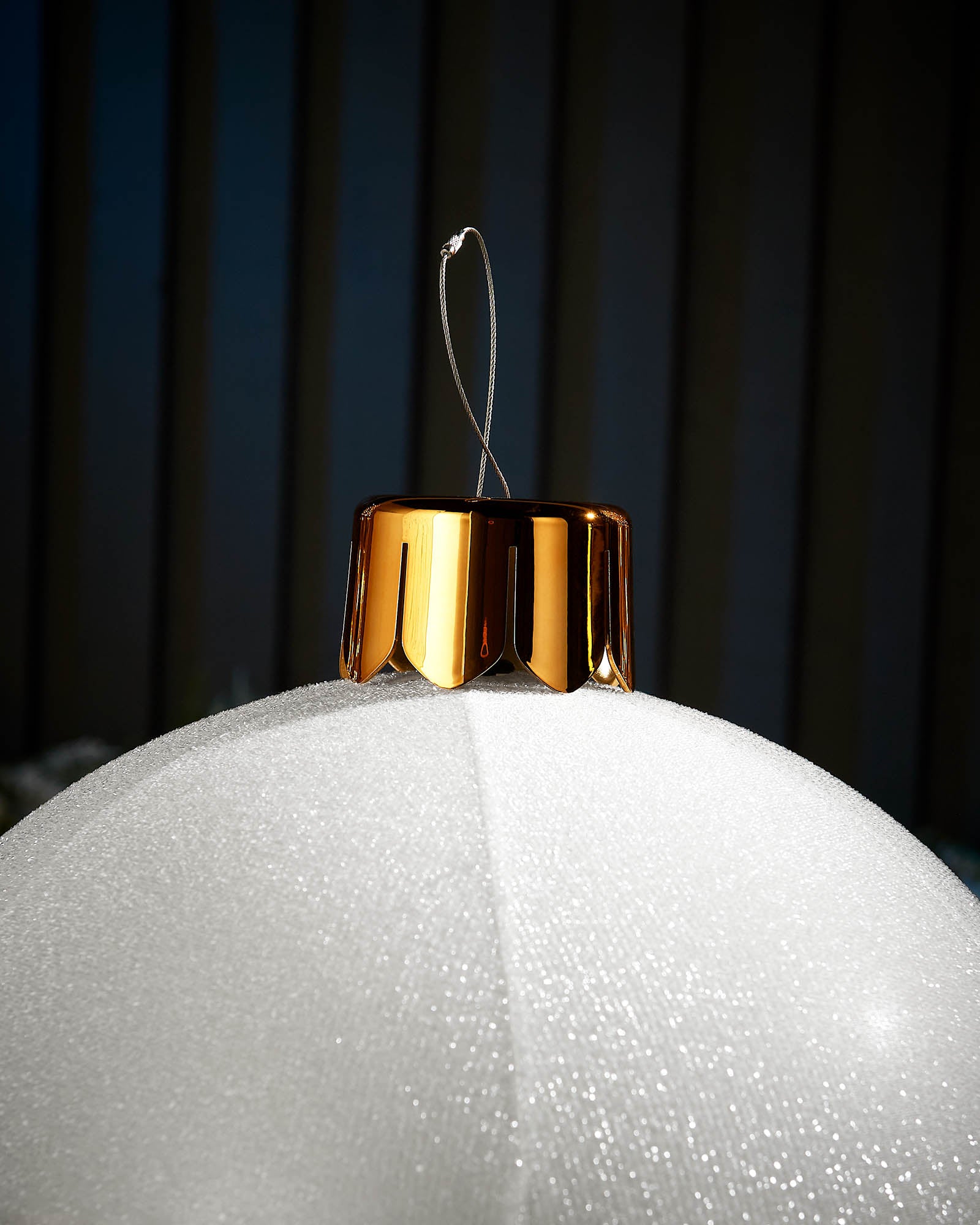 Close-up of the gold cap and hanging wire on a white 45cm inflatable tinsel Christmas bauble.