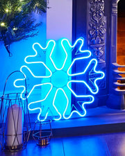 Blue snowflake neon rope light displayed indoors by a fireplace