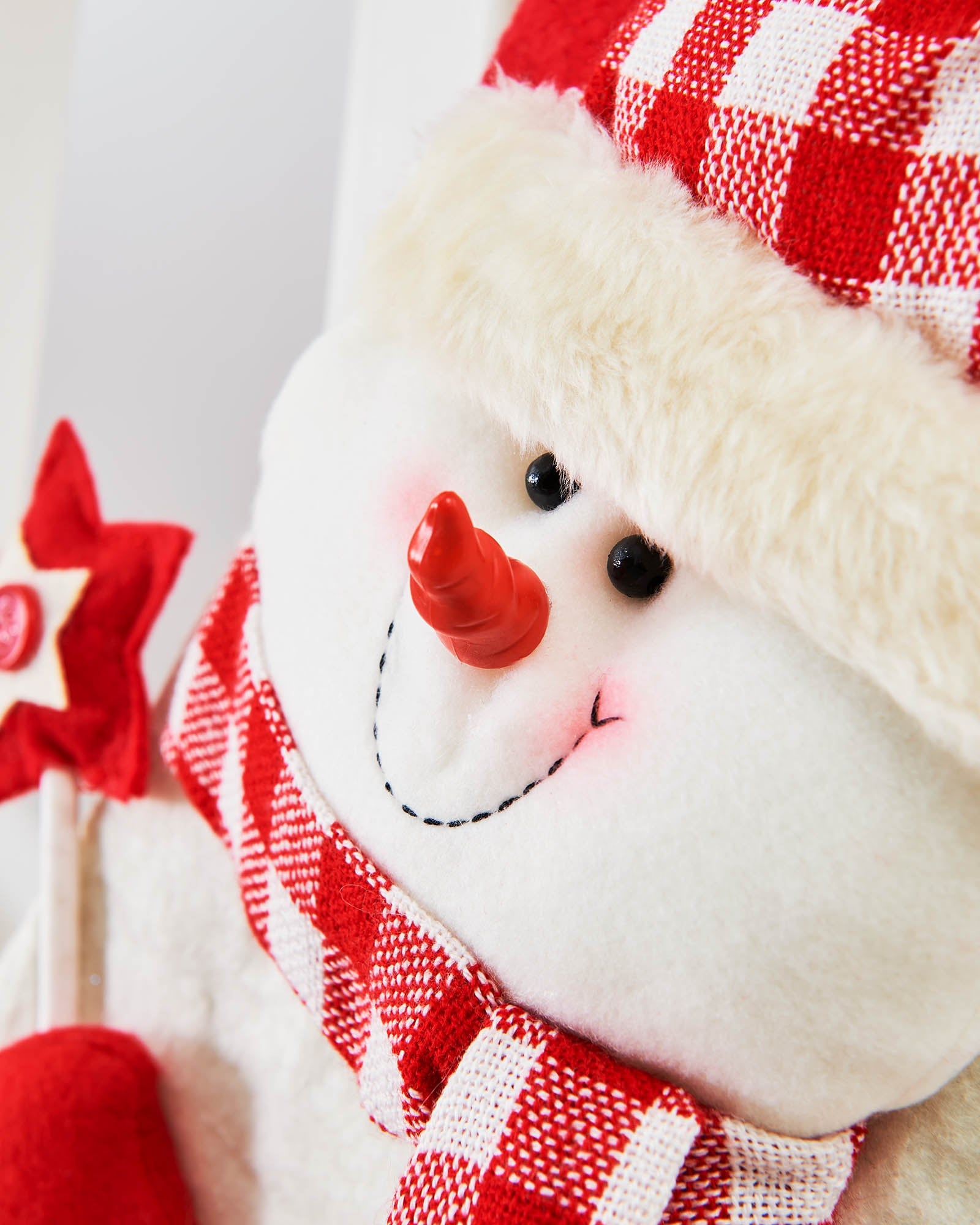 Close-up of the snowman face with red tartan hat and scarf on the Christmas stocking