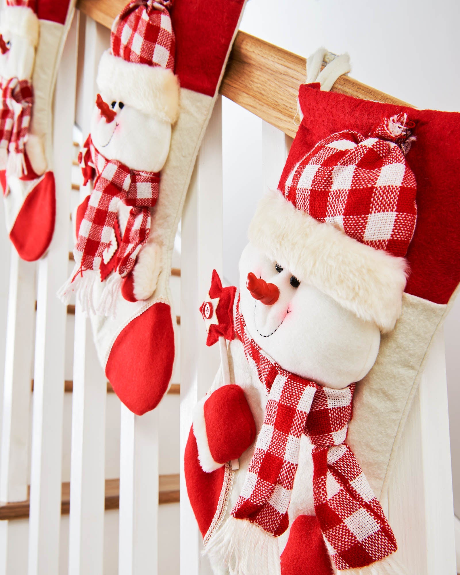 Tartan snowman Christmas stockings hanging along a staircase bannister