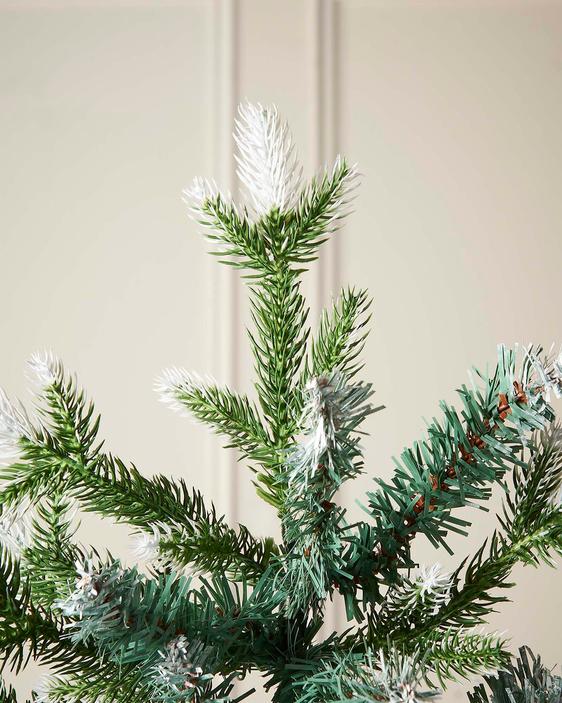 Life-like Evergreen Christmas tree with white snow-flocked tips and mixed cool green and blue tones, featuring hinged branches for easy assembly and storage—perfect for creating a trendy, rustic festive display indoors.