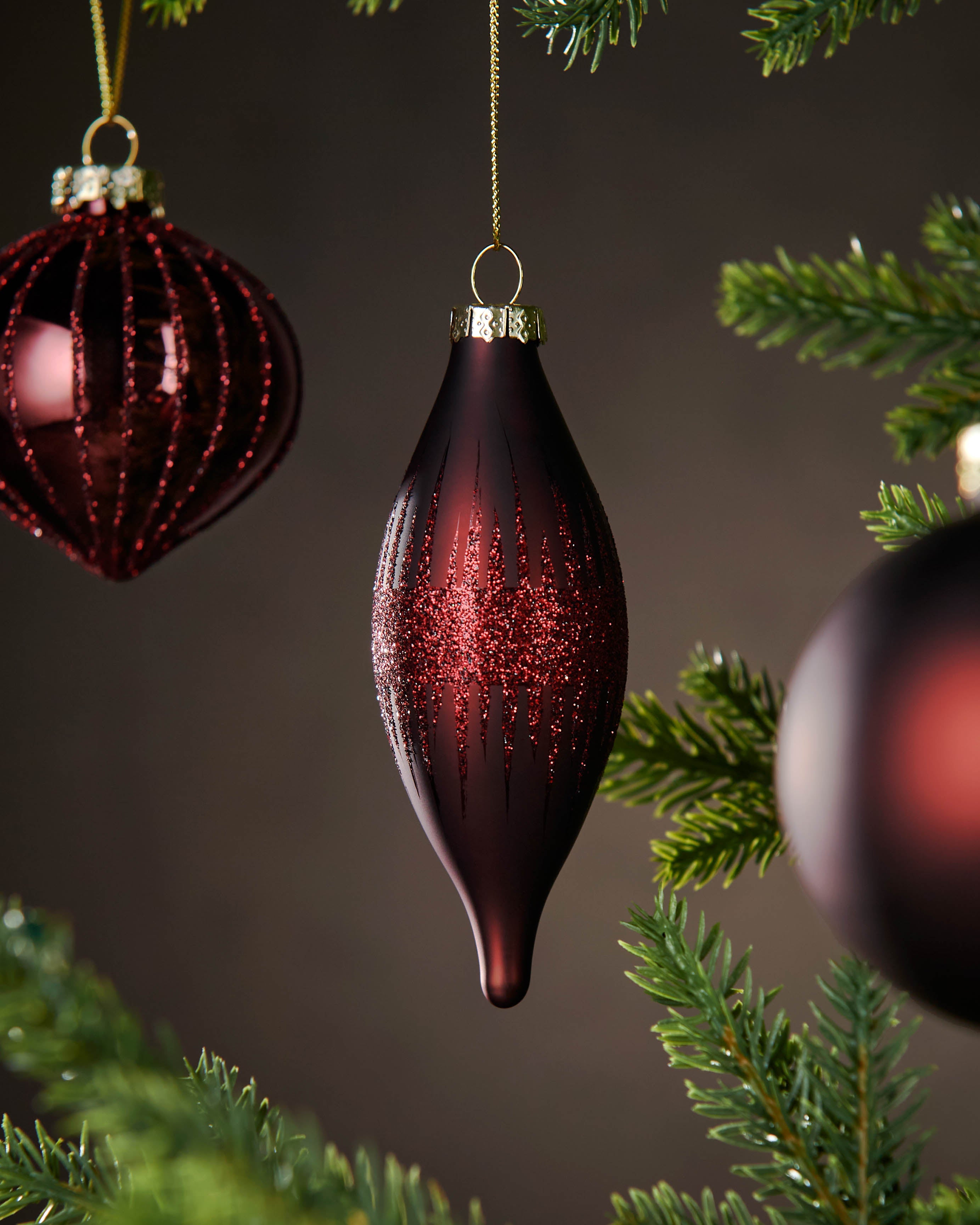 Red glass ornaments on a Christmas tree with a dark background