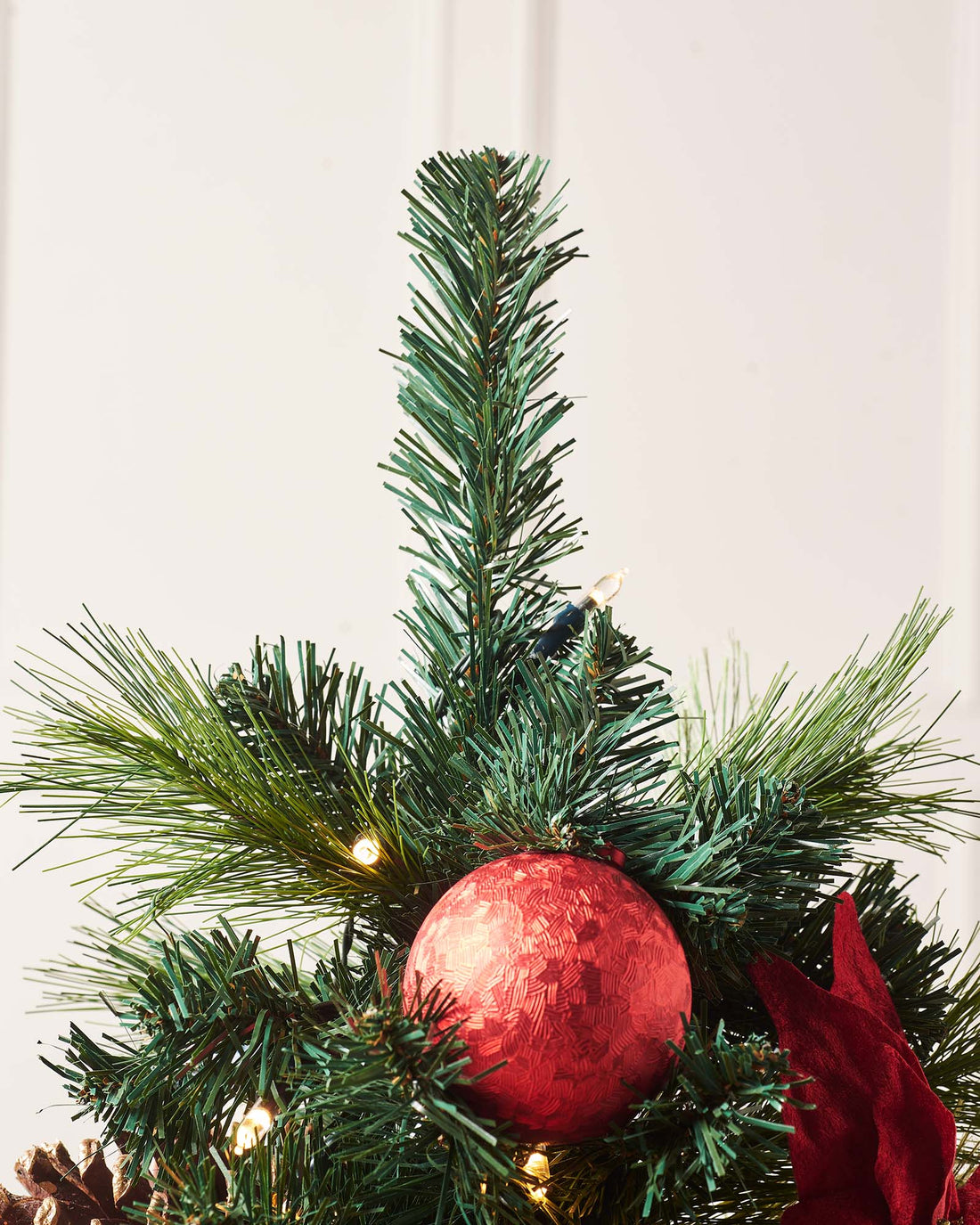 4-foot pre-lit potted Christmas tree with 140 PVC tips, warm white LED lights, red and silver baubles, pinecones, and berries, set against a white background.