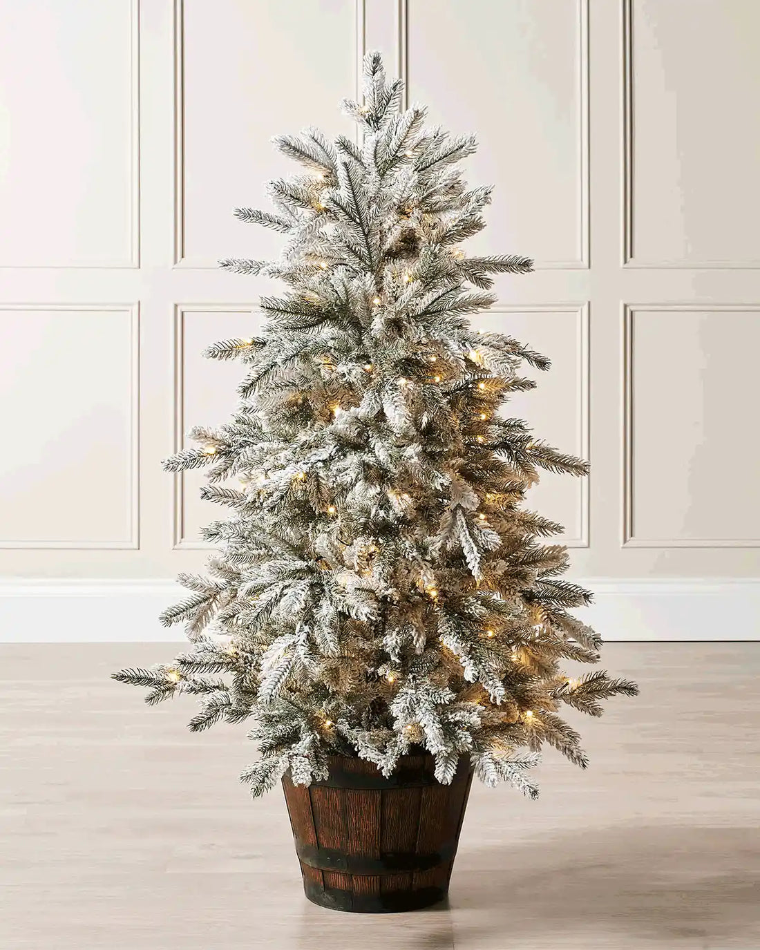 Pre-lit 4 ft snow flocked potted Christmas tree displayed in a decorative rustic pot with soft lights