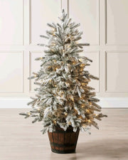 Pre-lit 4 ft snow flocked potted Christmas tree displayed in a decorative rustic pot with soft lights